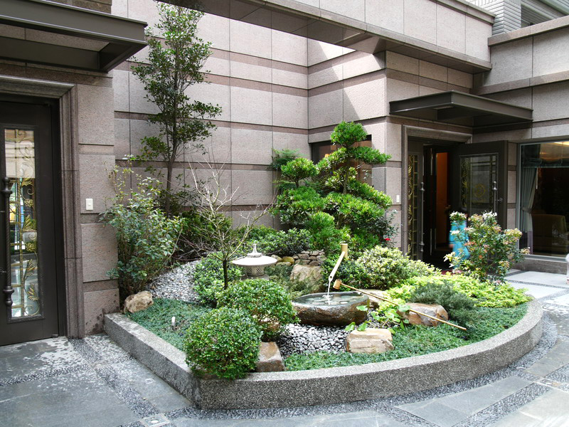 花台包覆綠意與修剪松木主景搭配水缽與石燈呈現日式庭院層次